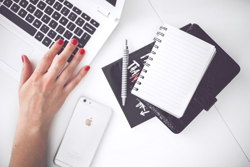 kaboompics.com_White laptop, female hand, note, pen, phone, desk